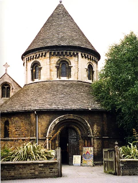 A historic circular stone church with a conical roof and an arched entryway with a dark wooden door.